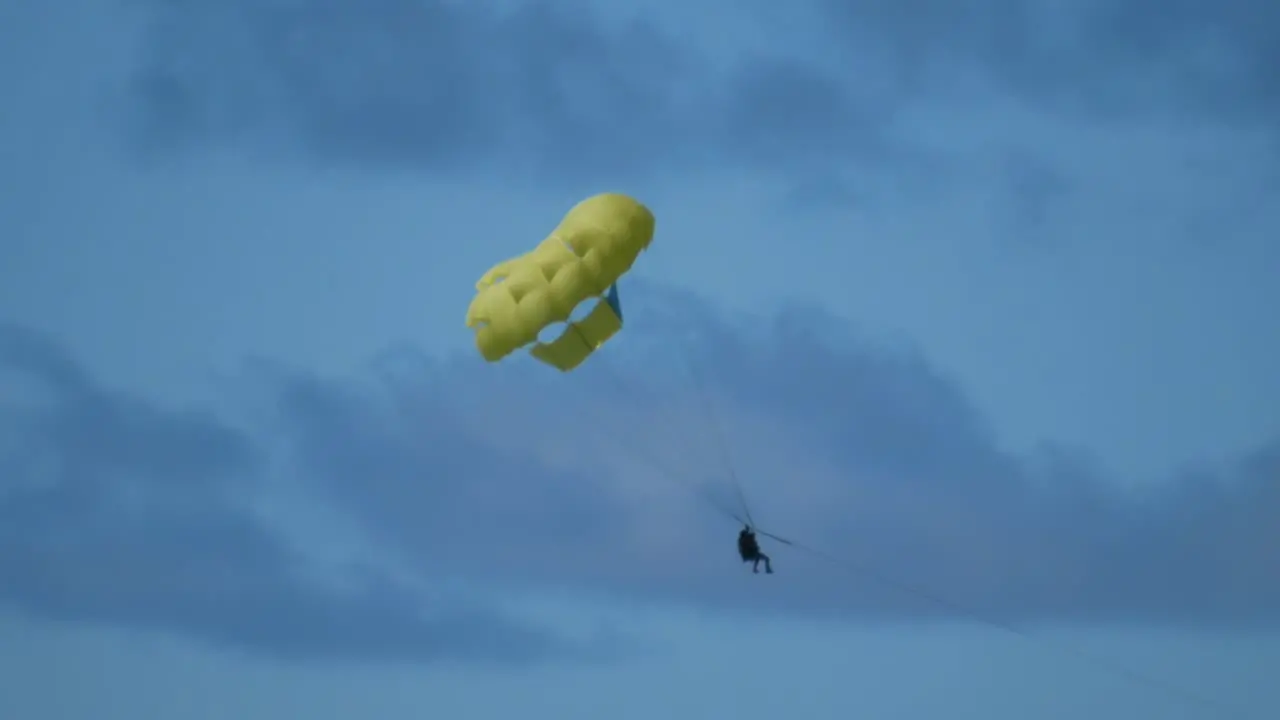 A couple doing parasailing hunging on a yellow parachute in a tropical island