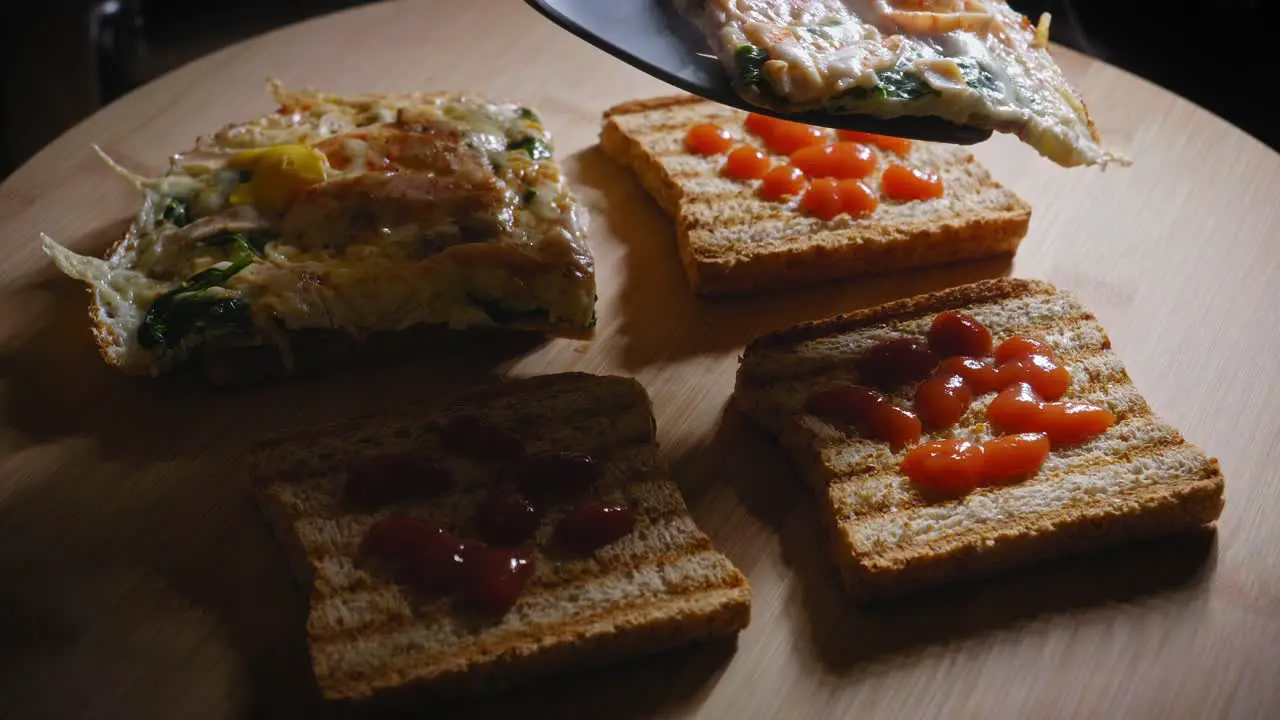 Putting fried egg with other ingridients on toasted toast close up