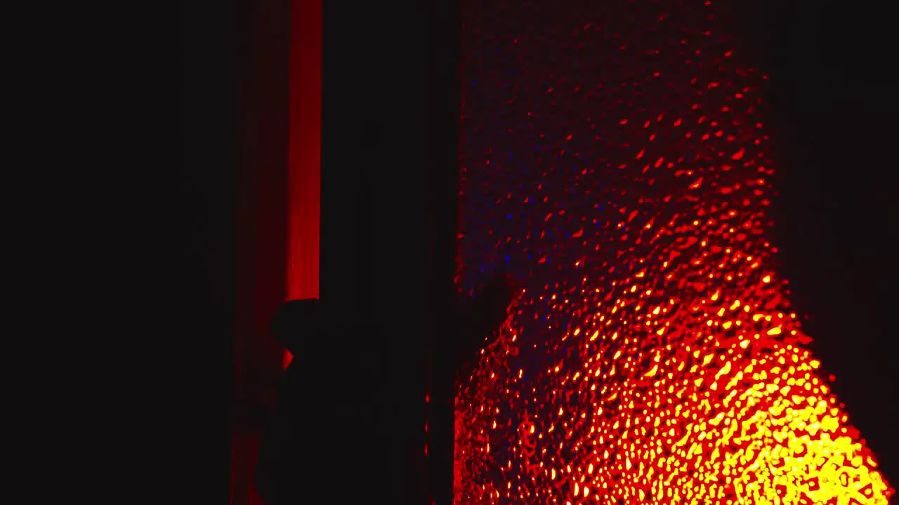 Sinister scary silhouette crawls opens glass door under red light