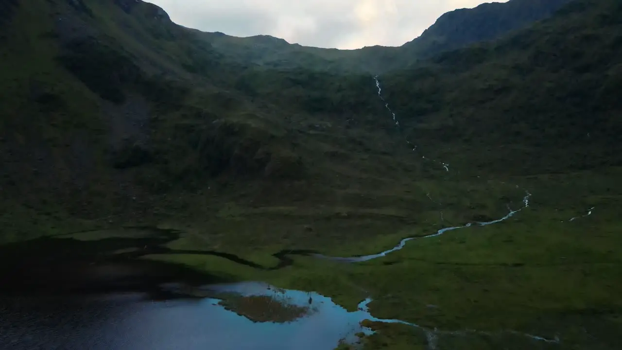 Aerial flyover Justadvatnet Lake and green slopes of cliffy mountains in Norway