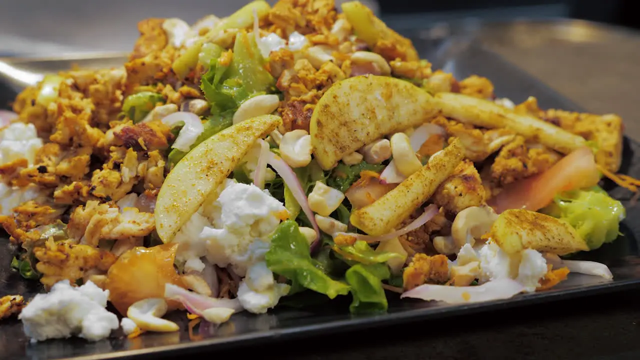 Nutritious salad piled with apples chicken goat cheese cashews slow motion slider pull HD