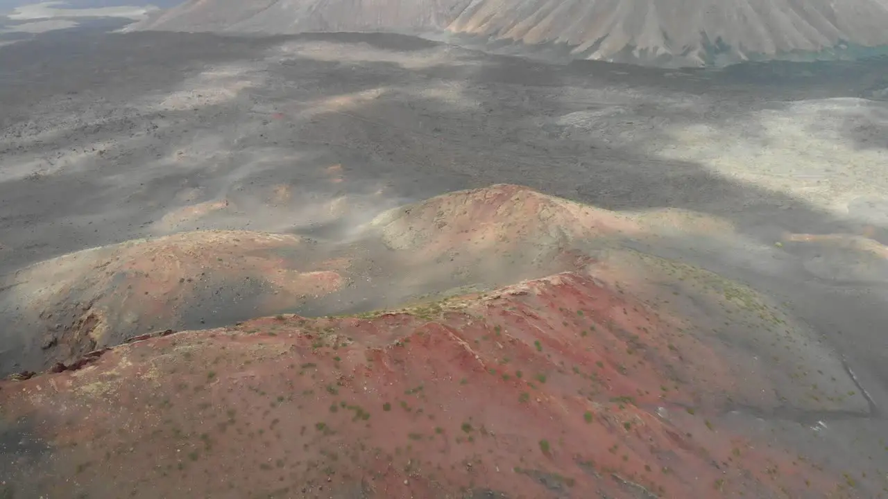 Pull back drone shot of a red volcano on a cloudy day