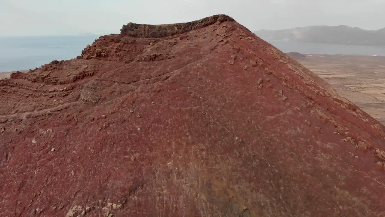 Flying over a red volcano with a tiny white building on top