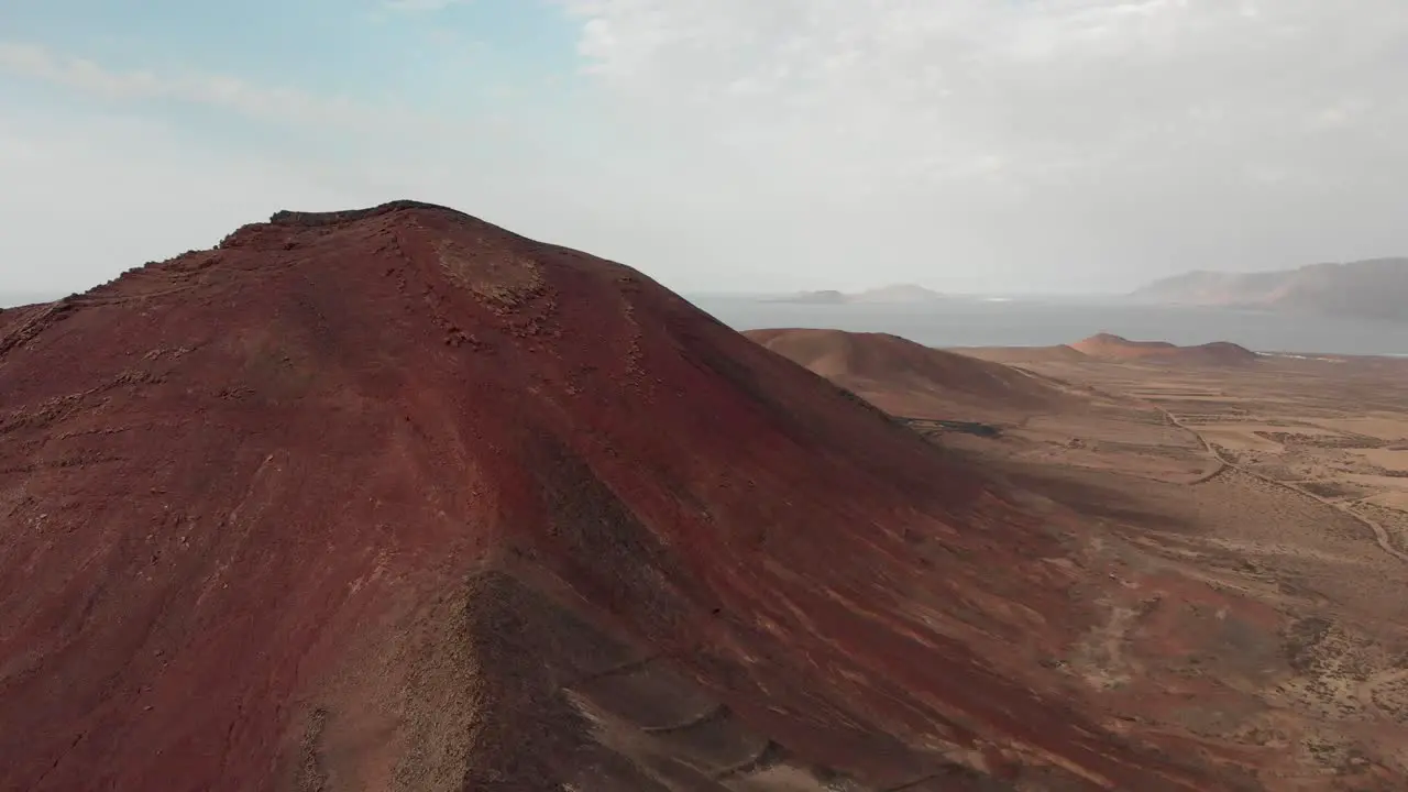 aerial view of a red volcanic landscape by the ocean