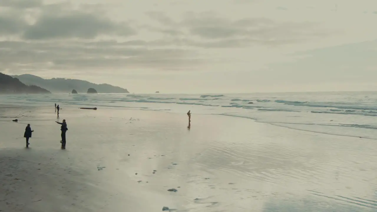 4k Aerial people on beach in Oregon Drone Dolly in + Job down