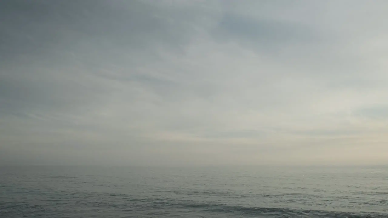 Wavy ocean water waves of Malibu on a dull cloudy day evening with passing clouds