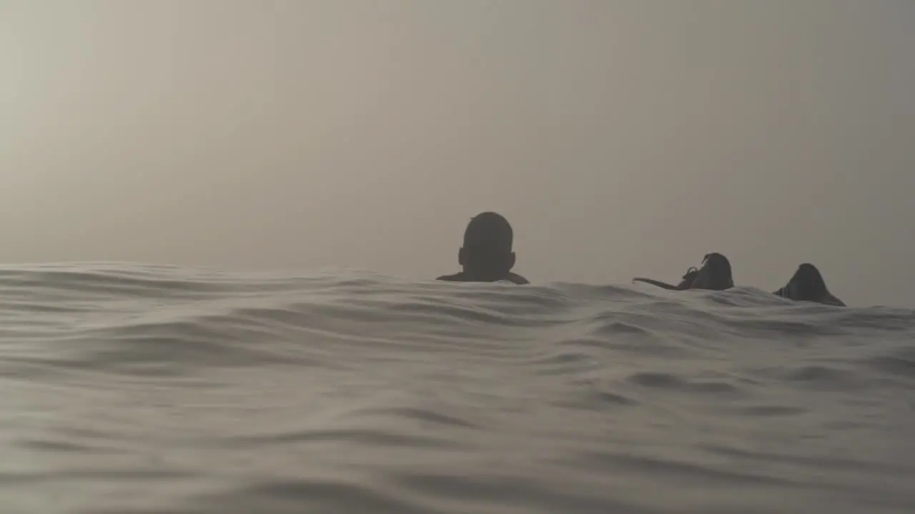 Silhouette of male surfer paddles in the ocean during foggy morning Slow motion