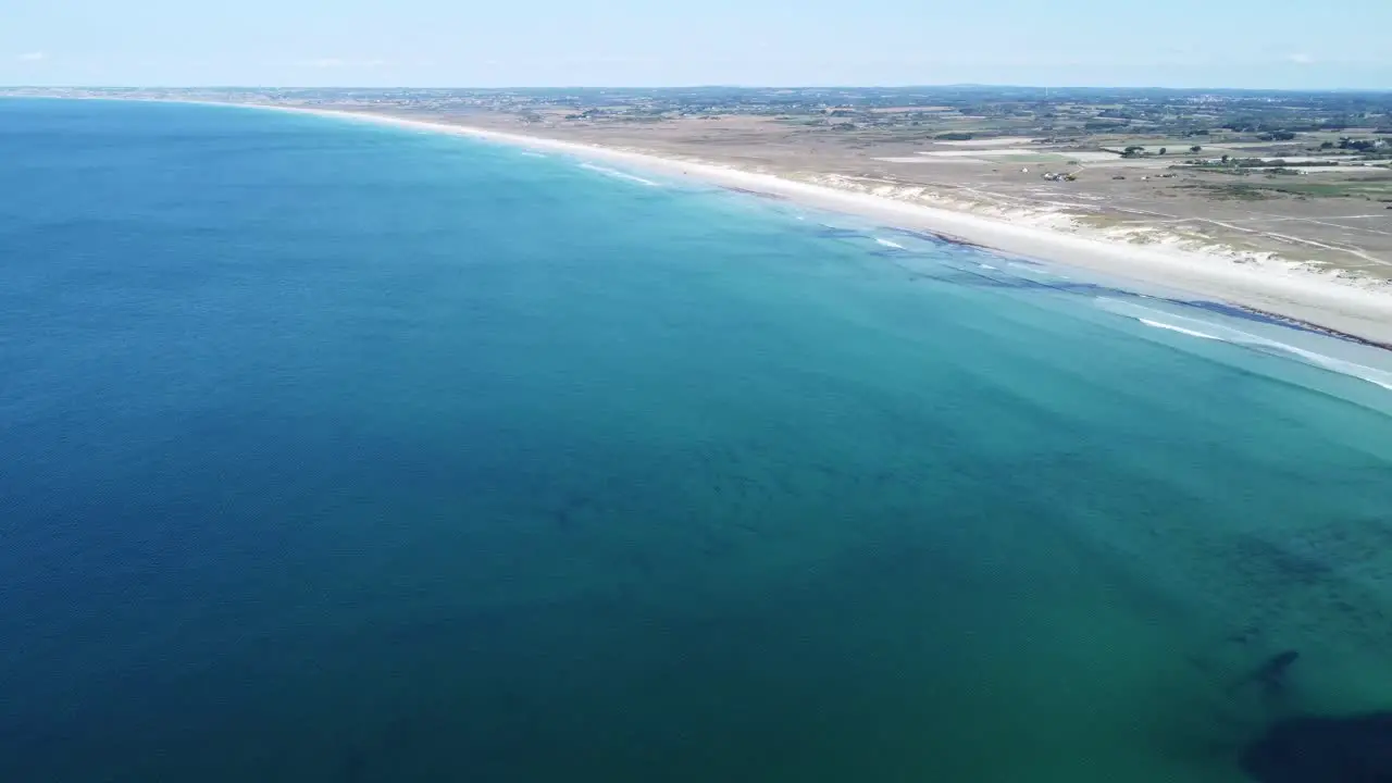 Endlessly long and white sandy beach near la torche in brittany in france filmed with a drone in perfect weather