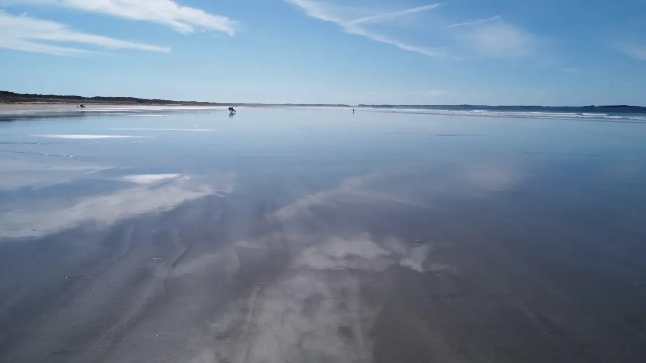 Drone filming just above wet sand at kerhillio beach in brittany clear blue sky