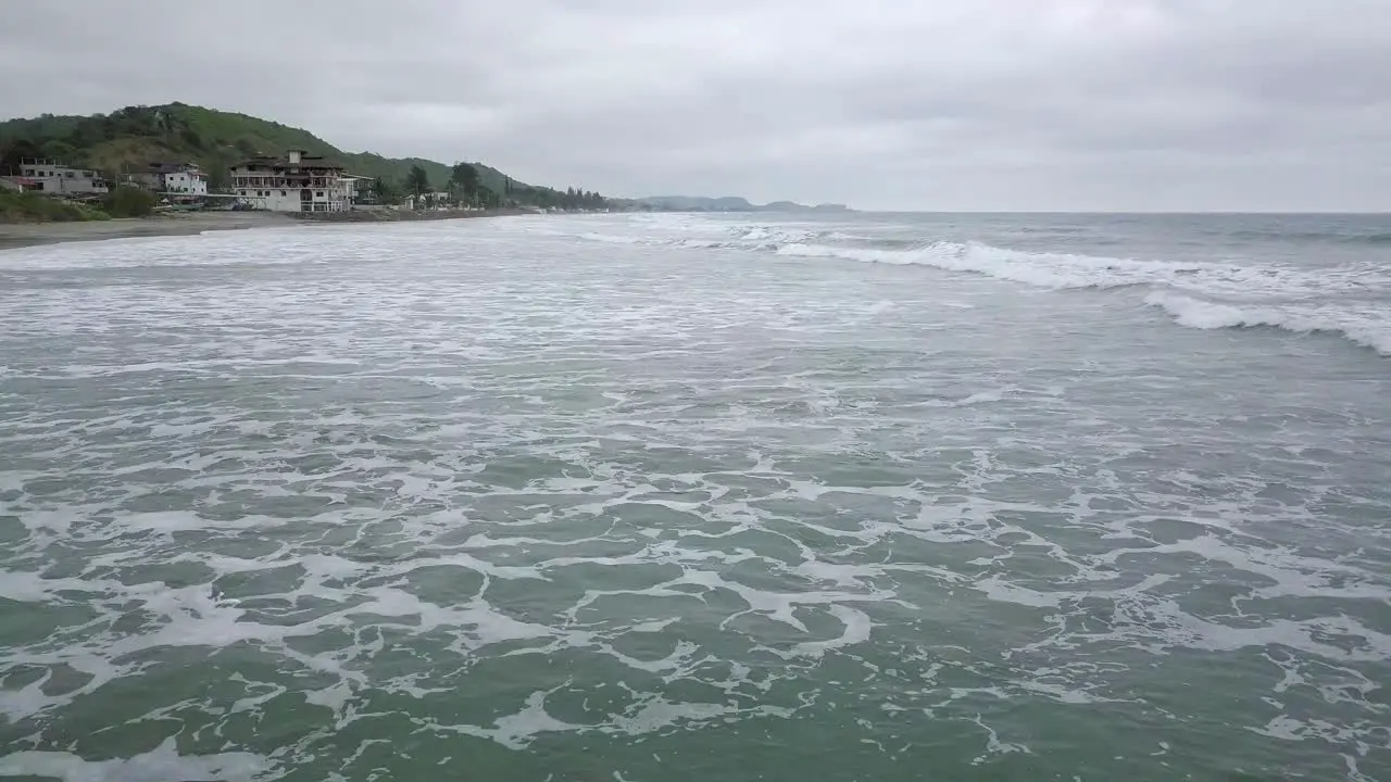 Aerial drone view of waves splashing at the shore of Olon beach in Ecuador