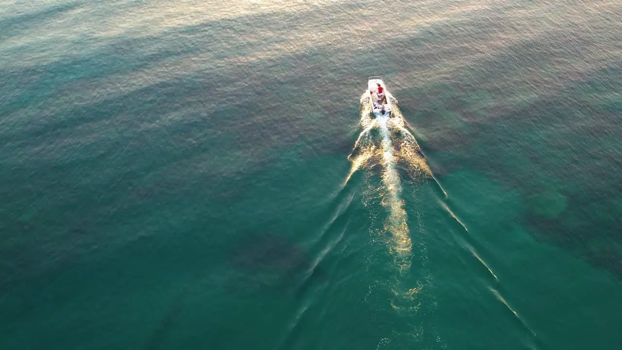 Aerial of a boat in the ocean camera goes up towards sunrise in Cyprus