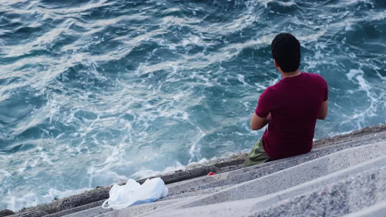 Man in front of a choppy ocean coast Muscat Oman medium high angle shot