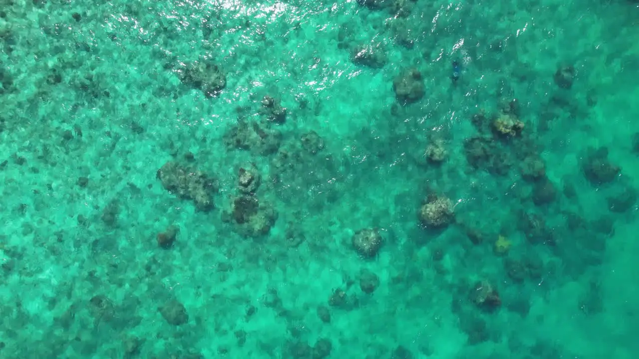 A drone is looking down on clear turquoise water flowing over rocks