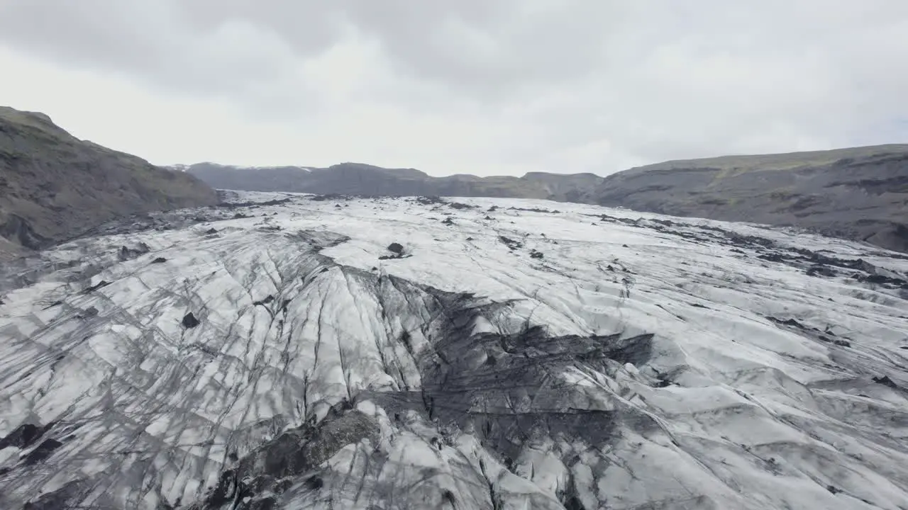 Aerial drone view above the blackened melting Solheimajokull Glacier in cloudy Iceland