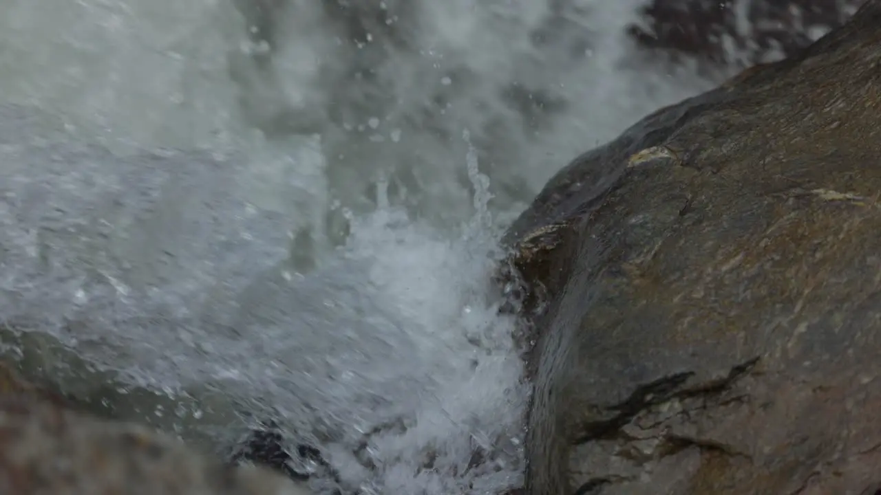 Detail closeup of water splashing powerfully against rock mountain waterfall