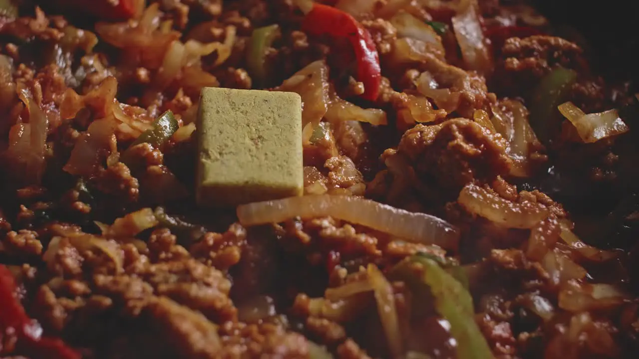 Adding stock cube to a recipe of meat and vegetables being cooked macro shot