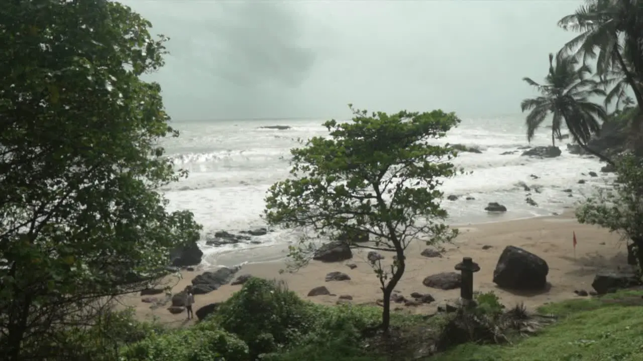 A slow motion shot of the crashing ocean waves at Grandmother’s hole beach in the distance grey storm clouds approach Goa India