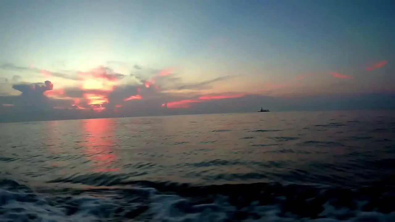 Sunset with a distant lightlight from a moving dingy after scuba diving in calm sea in Tubbataha Sulu Sea Philippines Asia