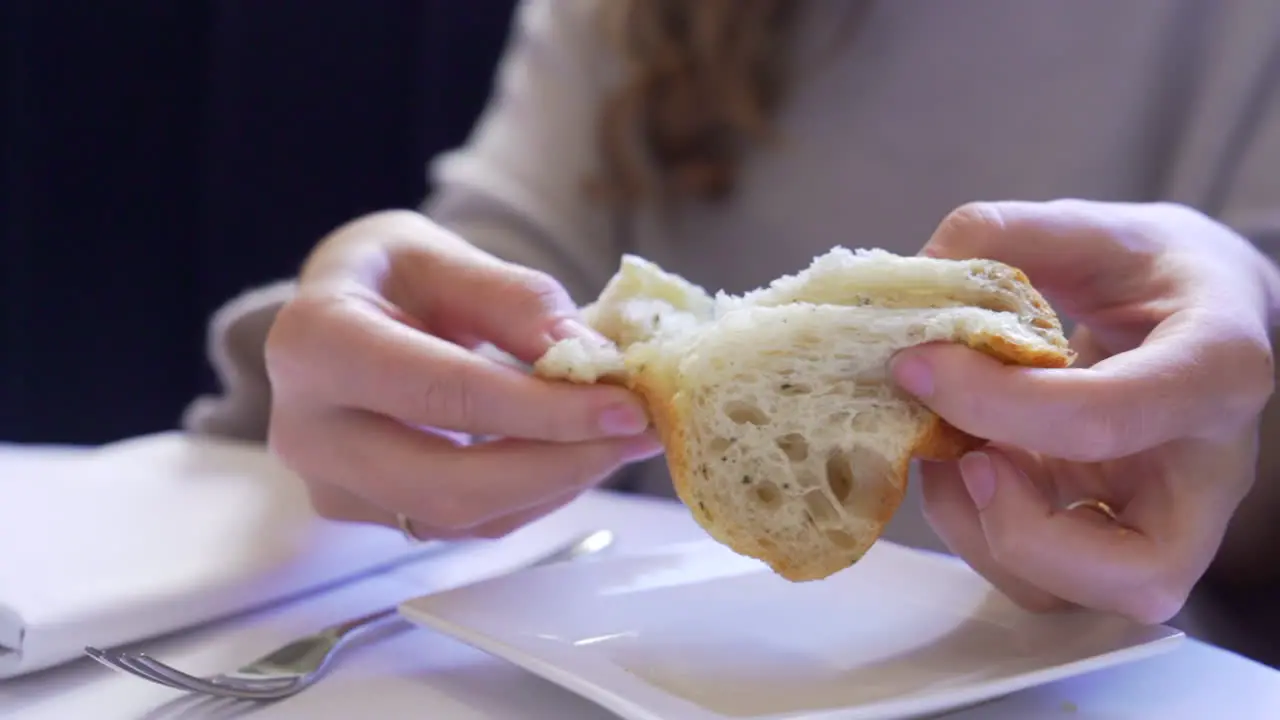 Woman's hands tearing bread at a restaurant table