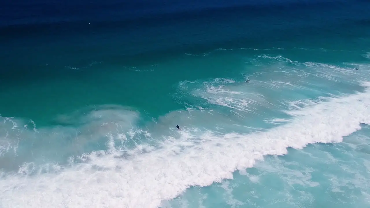 Surfer duck diving under a wave distant drone shot