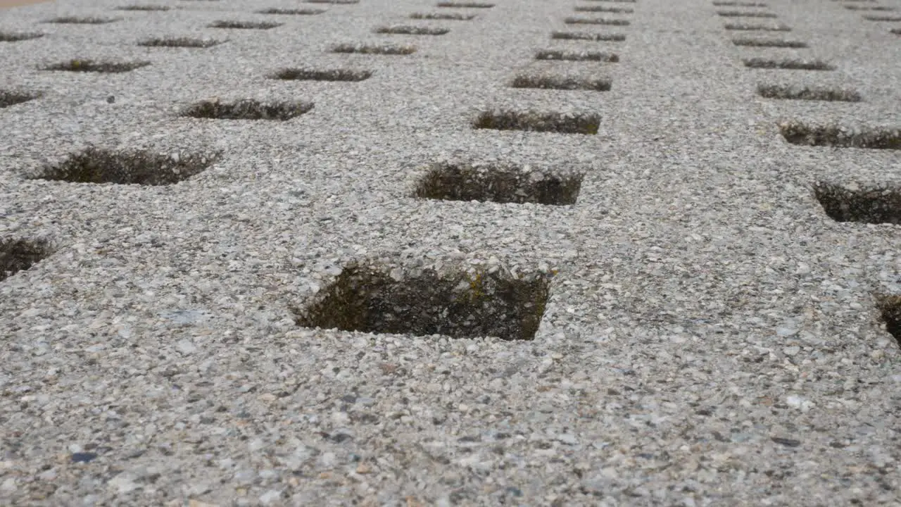 Low angle repeated geometric stone square holes carved in granite marble surface dolly left