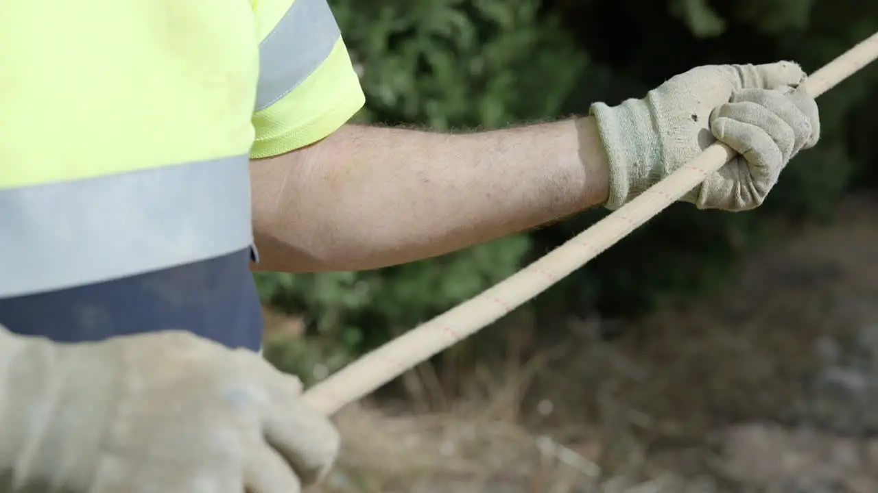 Contractor holding guiding rope pulling heavy industrial equipment close up