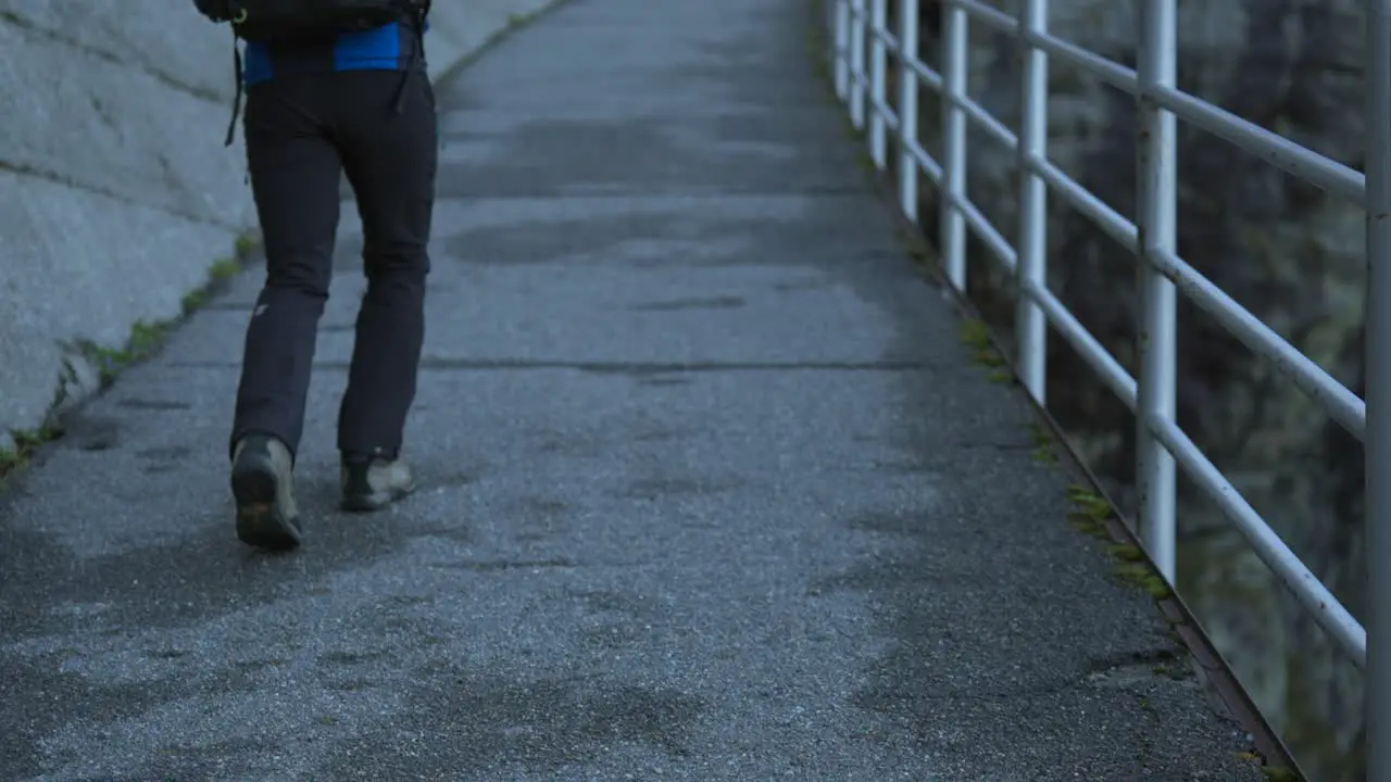 Hiker walking along a concrete slope and a metal railing