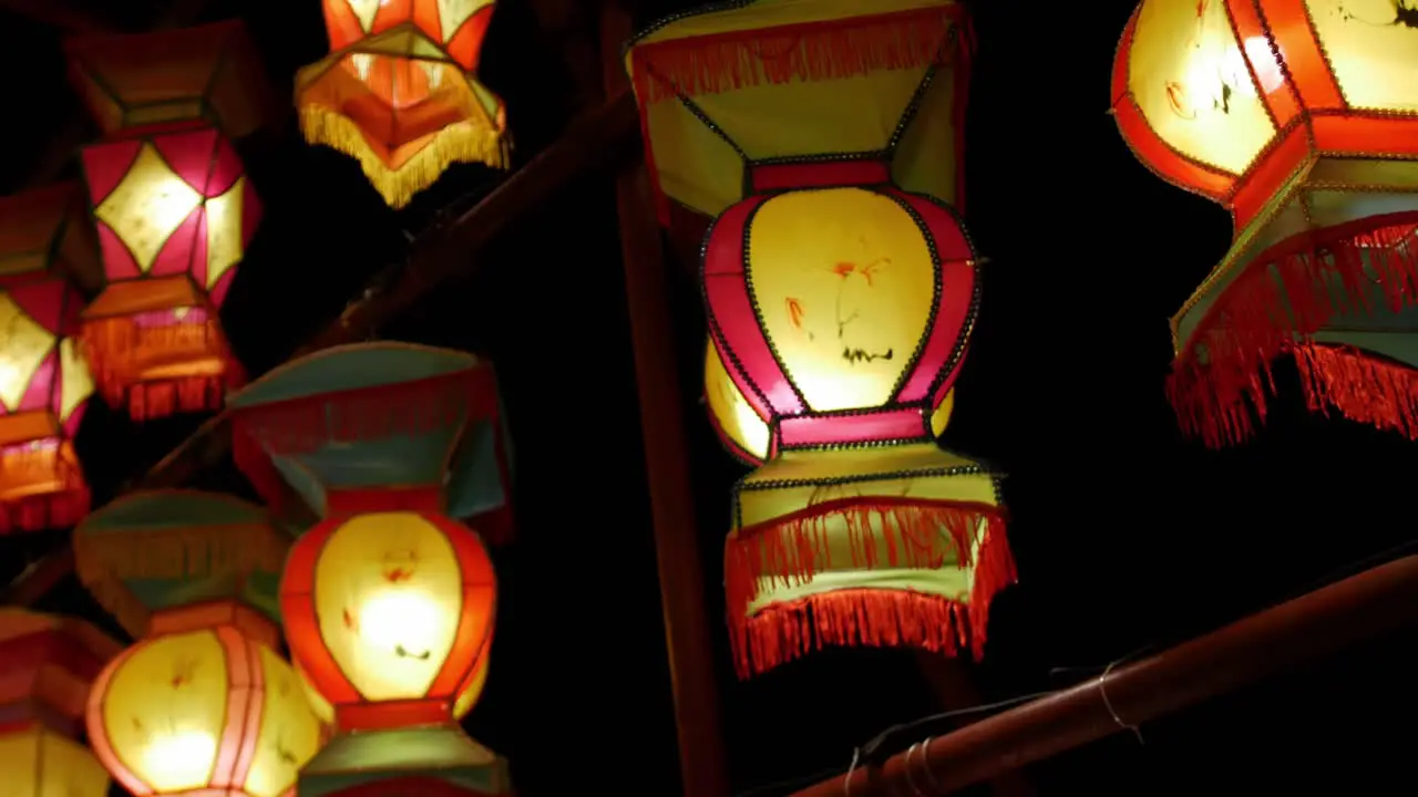 Chinese lantern lights hang as the camera quickly passes by against a night sky