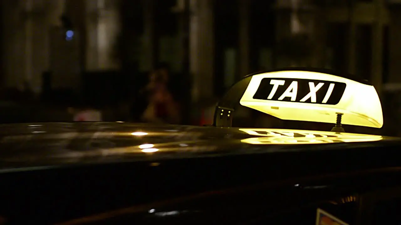 taxi lighting sign arriving while the taxi parks in the city at night