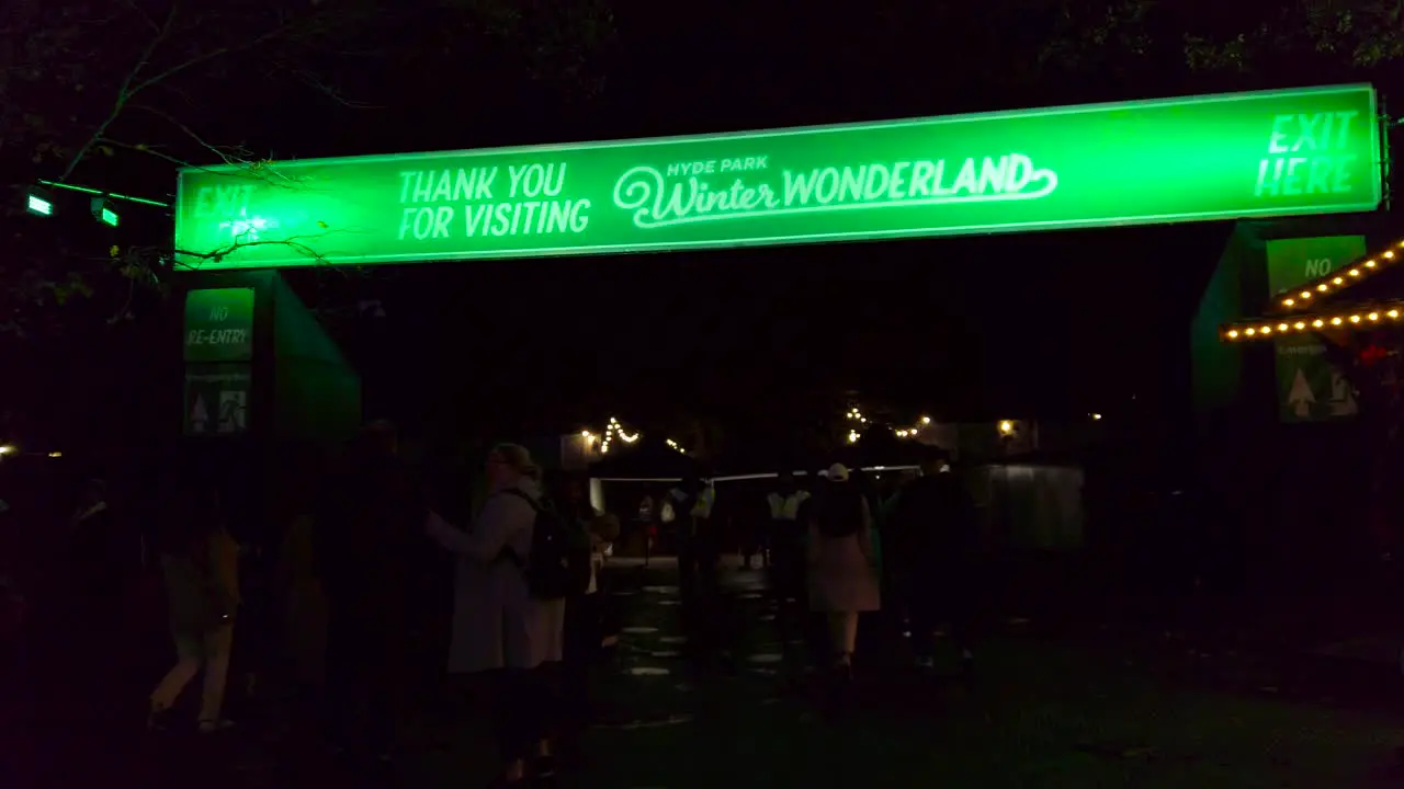 Close up shot of locals exit path of winter wonderland through main entrance in London UK at night time