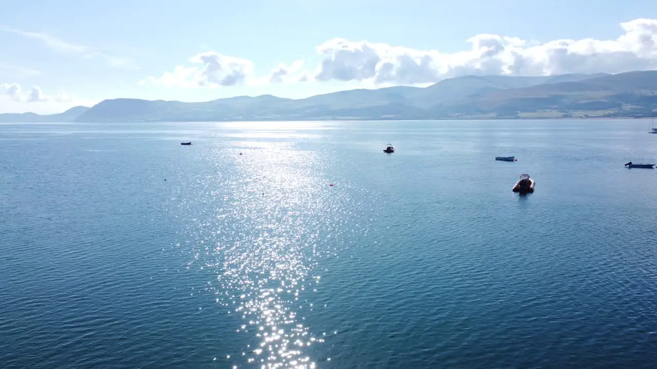 Snowdonia clear mountain range aerial view sunny calm Welsh shimmering seascape dolly left