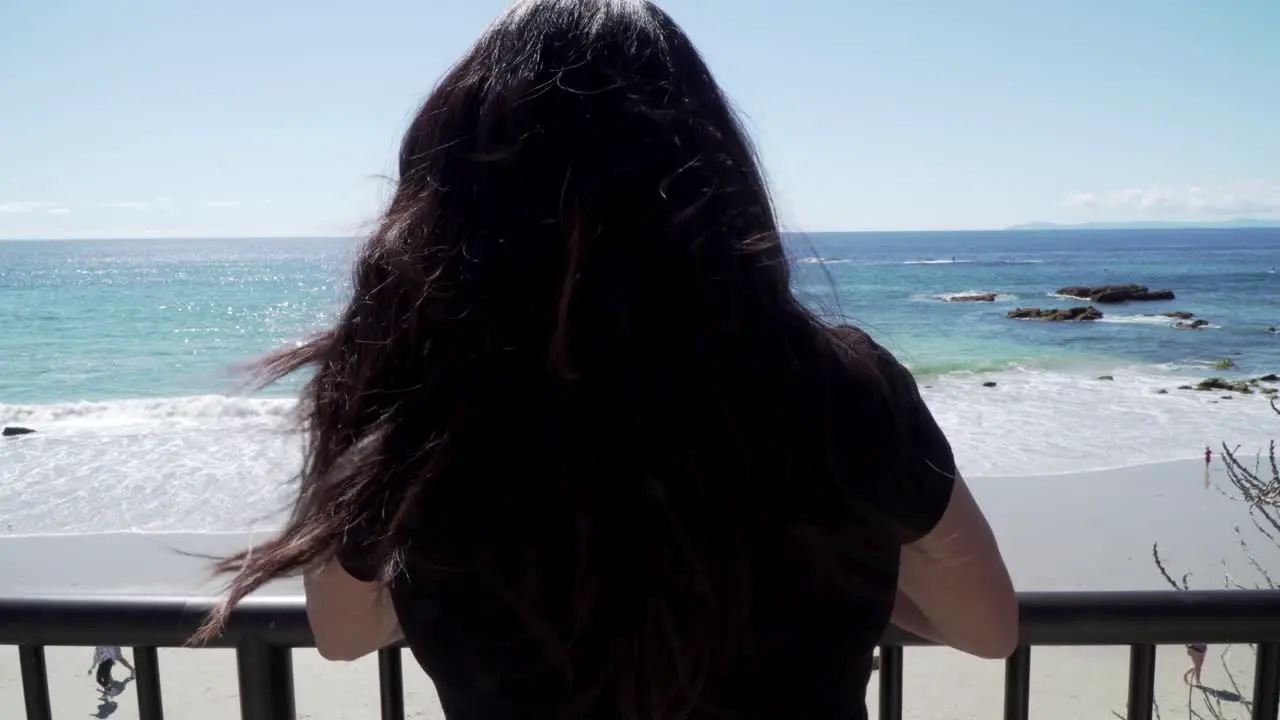 Woman looking over at the sea standing on the view point on the beach