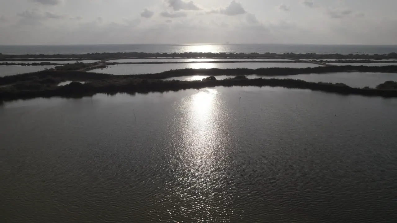 Aerial view in forward flight of fishing ponds by the sea mirror silhouette slow motion