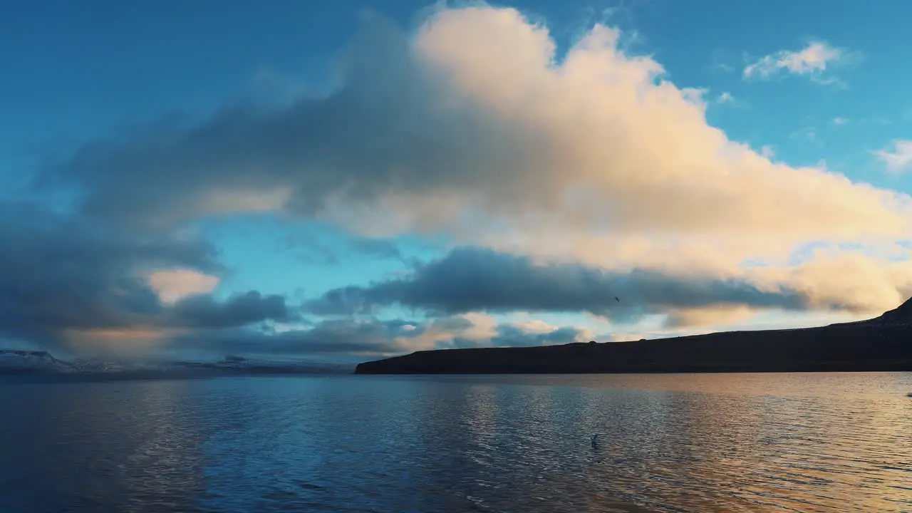 Beautiful view of birds landing on the sea skies with clouds and mountines in the background