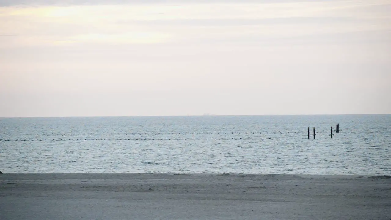 Wide shot over a deserted sandy beach and the sea with buoys demarcating a swimming area