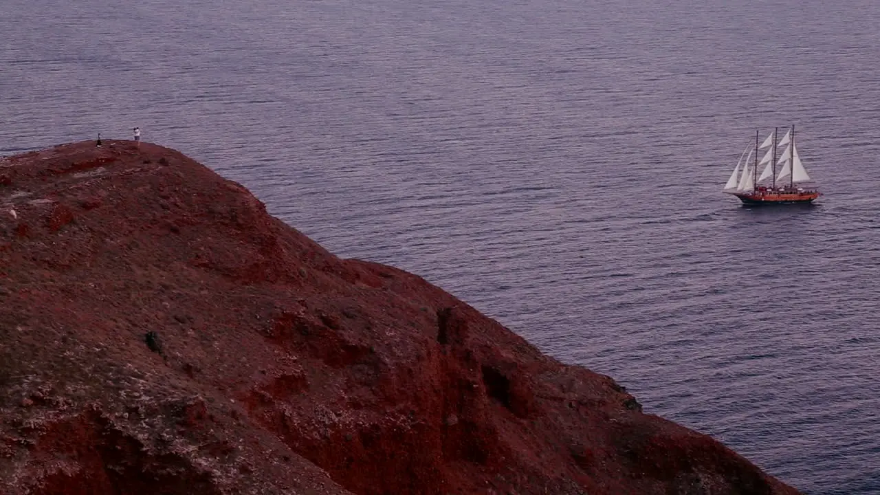 A beautiful sailing ship sails near some islands at dusk