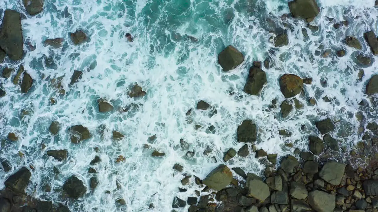 Aerial view of waves crashing on the rock beach