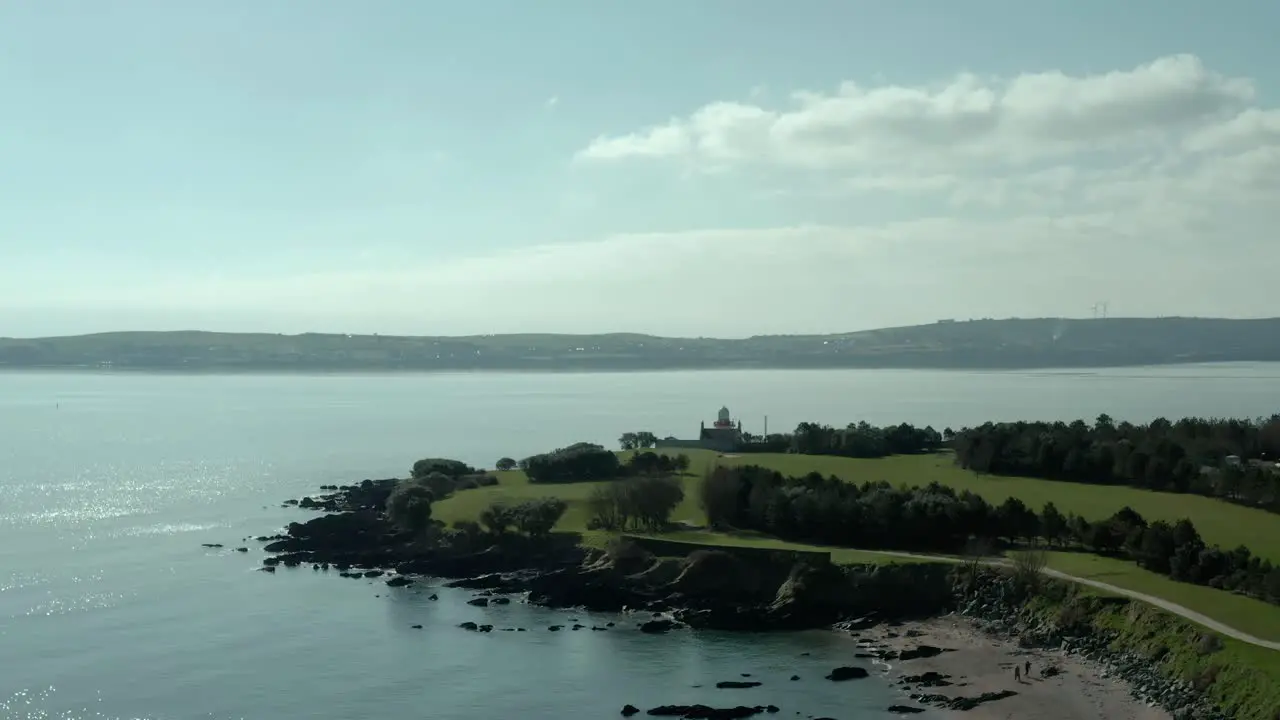 Aerial wide angle of flying over ocean sea coast at day lighthouse at back