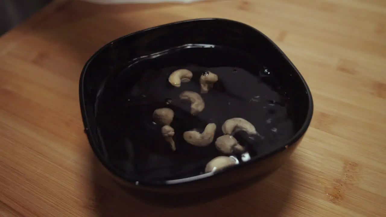 Peanuts dropping into a black bowl with water for soaking