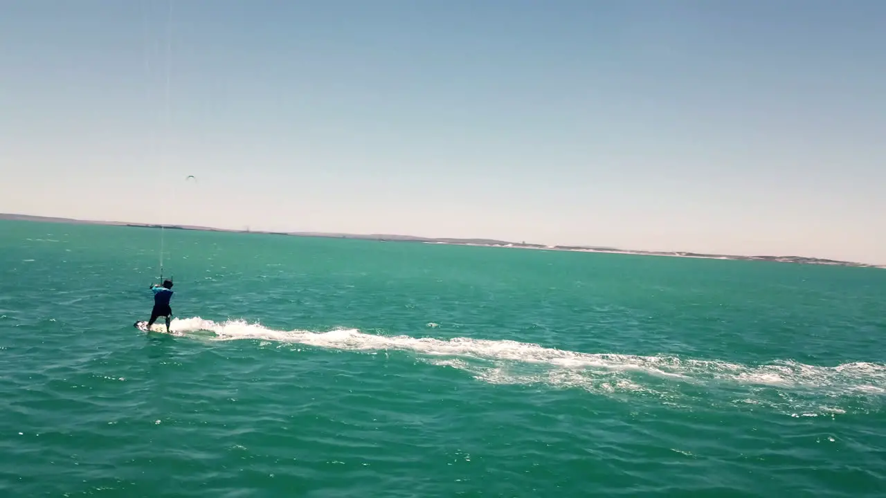 Professional watersports kite-surfer drone wide shot during beautiful natural daylight blue sky and splashing turquoise water on the open ocean in Cape Town South Africa