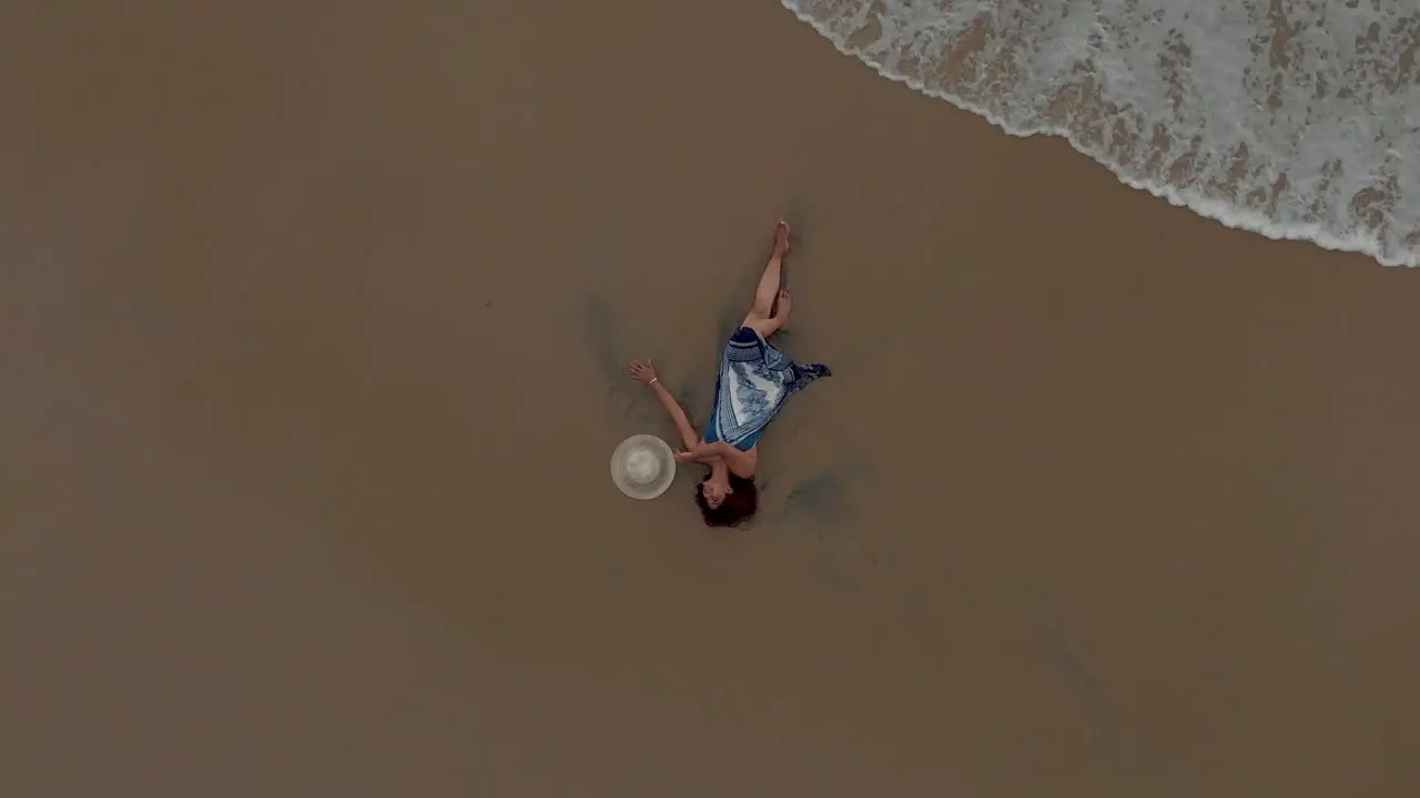 4k Aerial Top Down Drone shot of A pretty 27-year-old young Indian woman getting drenched by the sea waves along the shores of Varkala