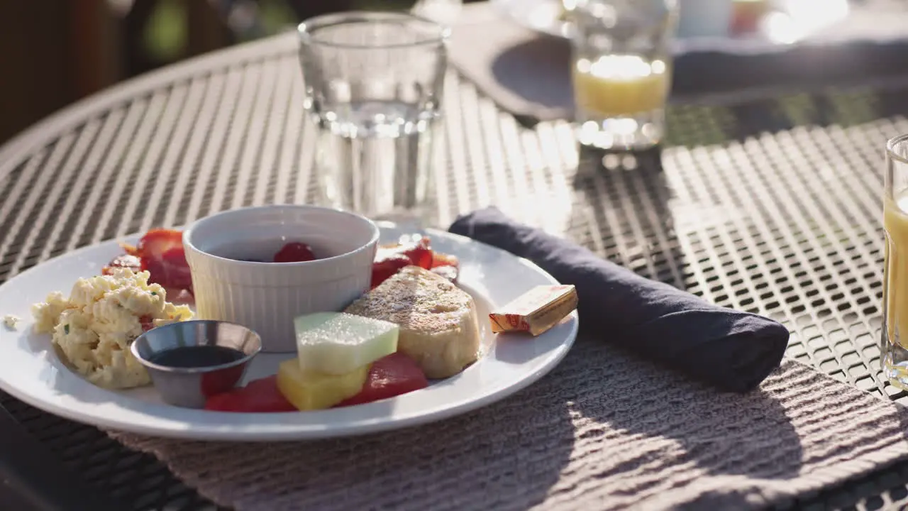 Pan over a colourful breakfast plate outside table in sunlight