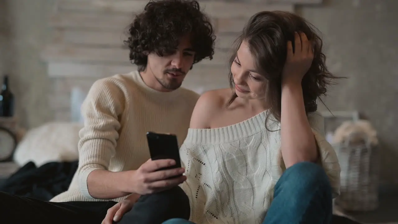 Linda Pareja Joven En La Cama Mirando Algo Divertido En El Teléfono Y Riendo