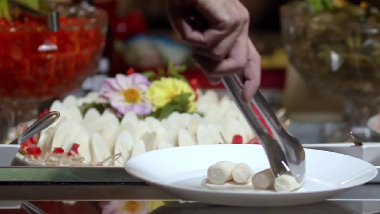 Close-up of a person's hand serving gourmet vegetables on a plate from a colorful platter