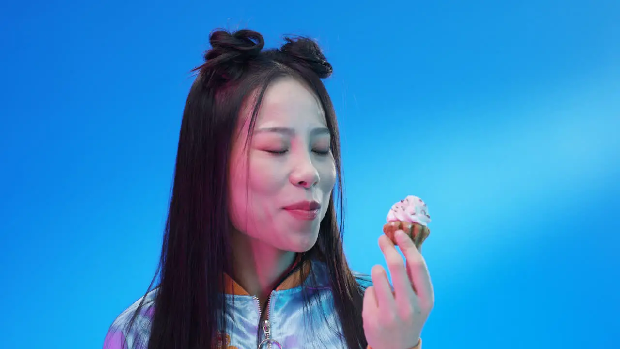 Close Up Of Woman Eating Little Cupcake With Pink Cream