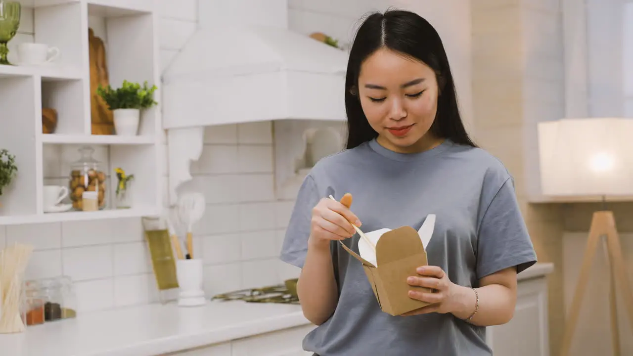 Happy Japanese Girl Eating Takeaway Ramen While Looking At The Camera And Smiling