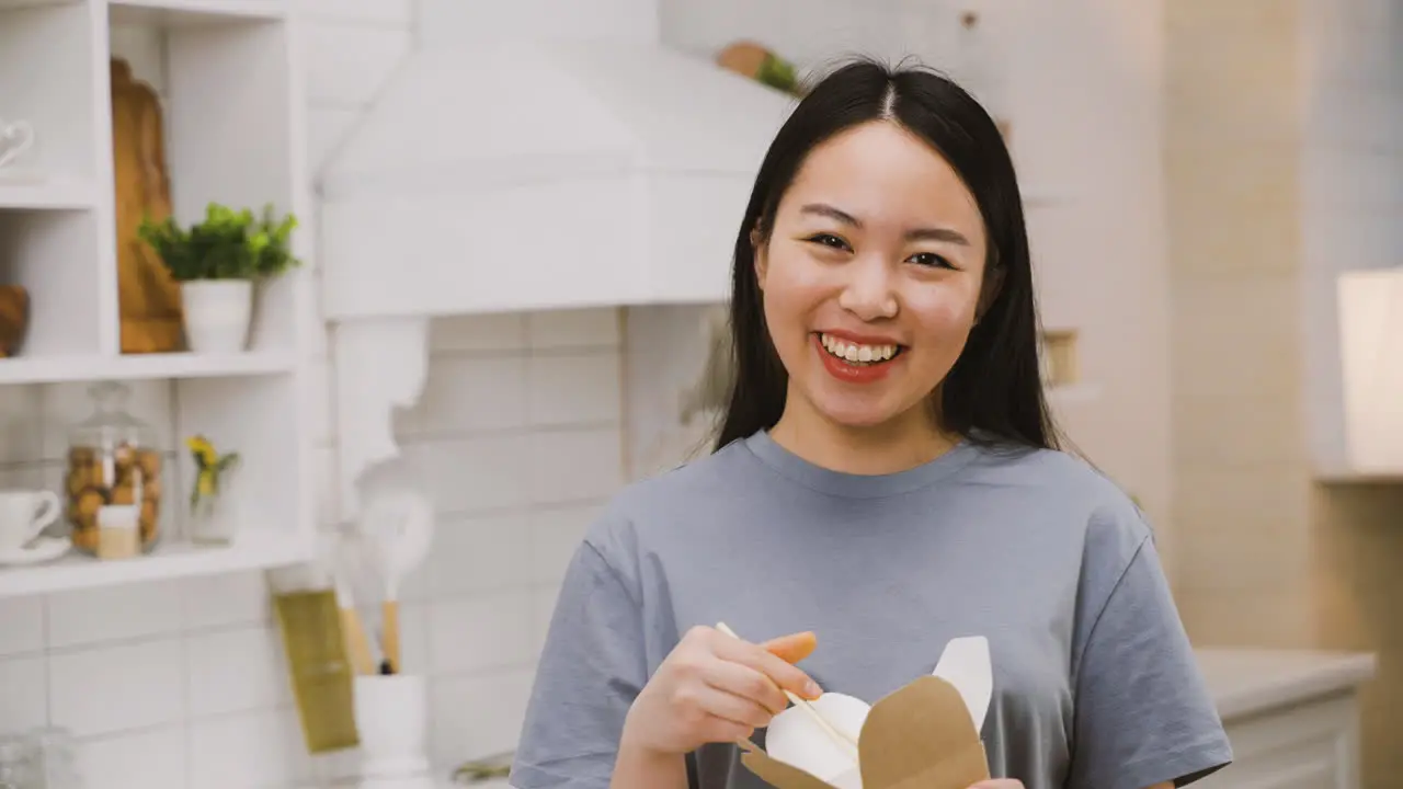 Happy Japanese Girl Eating Takeaway Ramen While Looking At The Camera And Smiling 1