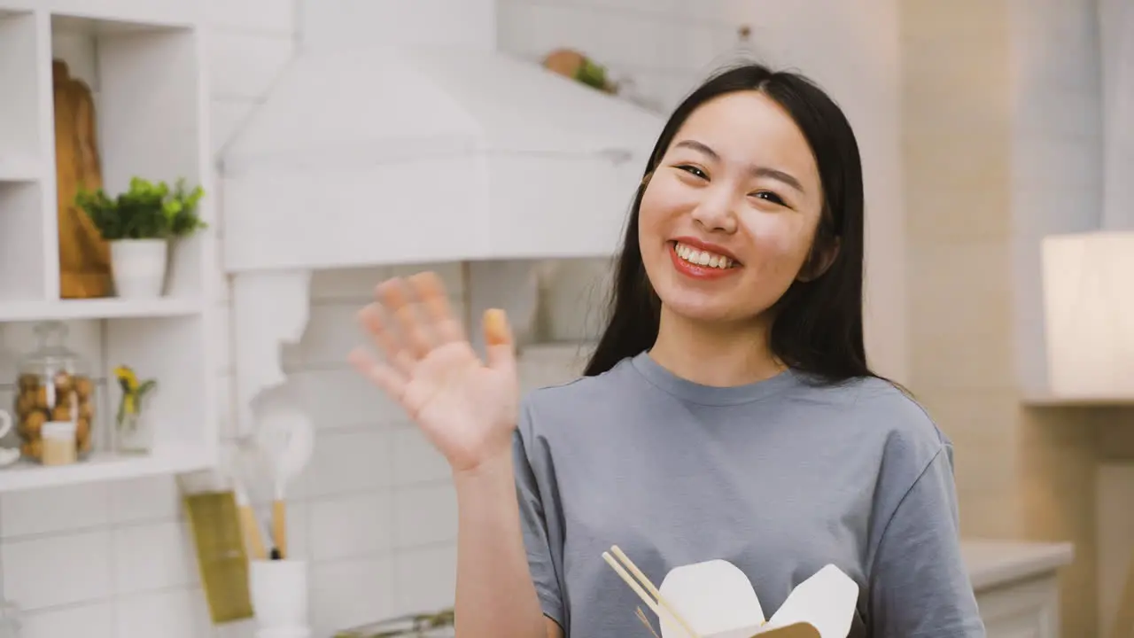 Happy Japanese Girl Eating Takeaway Ramen While Looking At The Camera And Waving Smiling