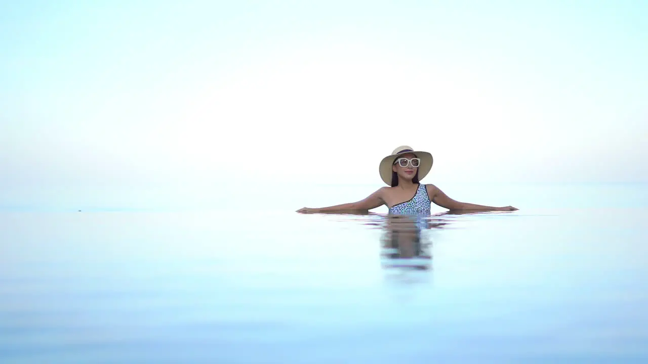 Paradise Like Scenery Exotic Woman in Infinity Swimming Pool With Bright Endless Horizon in Background Full Frame