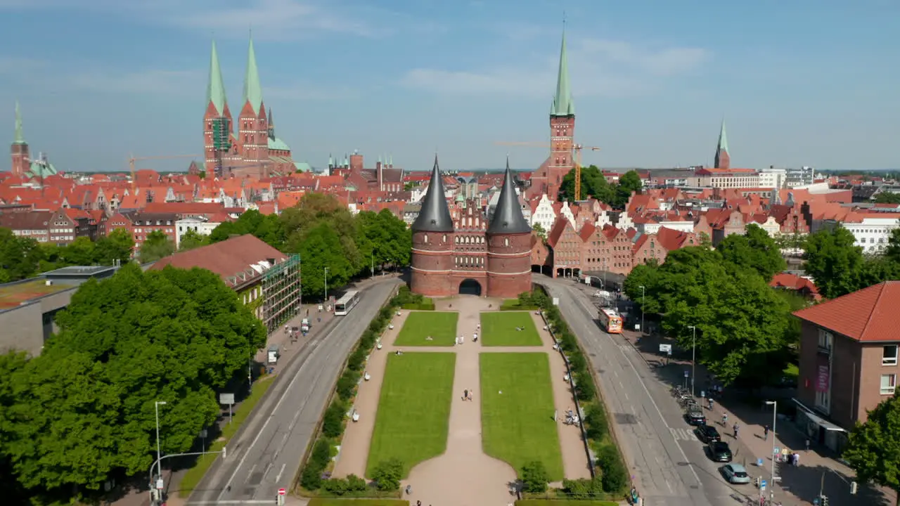 Tilt up forwards reveal of historic centre of town Red brick houses churches and buildings Fly between towers of Holsten Gate Luebeck Schleswig-Holstein Germany